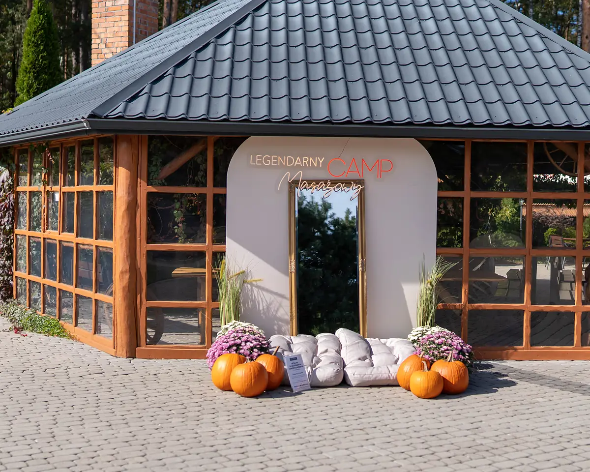 A pavilion with the sign Legendarny Camp Masażowy, pumpkins and cushions in front of the entrance