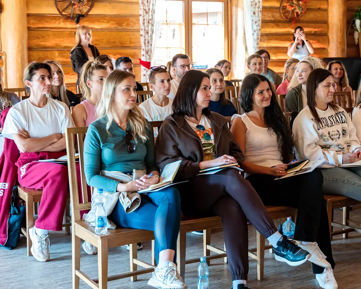 A full room of camp participants with notebooks on their laps