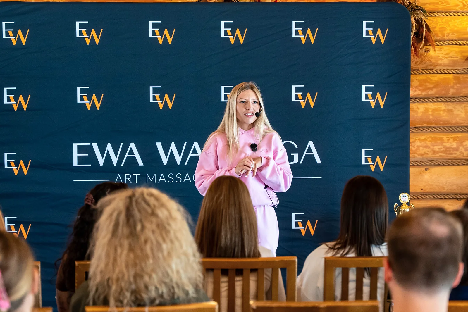 Ewa Wardęga speaks to camp participants in front of the Art Massage Academy backdrop
