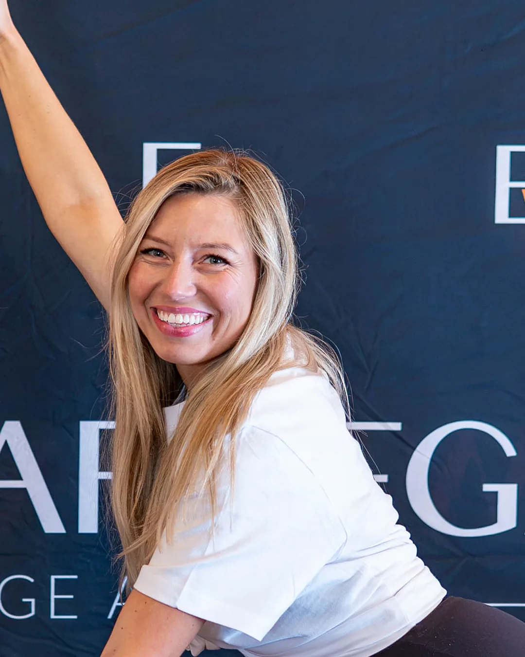 Ewa Wardęga smiles at the camera, raising one hand